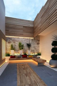 an outdoor living area with wooden flooring and potted plants on the side wall