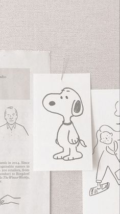 some drawings are hanging on the wall next to papers with pictures of people and dogs