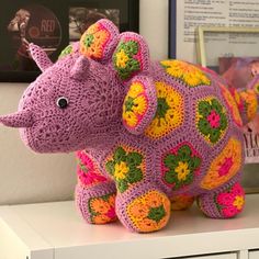 a crocheted stuffed animal sitting on top of a white shelf next to a wall