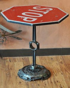 a red stop sign sitting on top of a metal stand next to a wooden floor