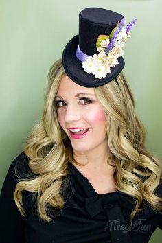 a woman wearing a black top hat with flowers on her head and long blonde hair