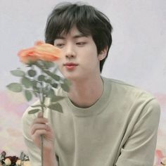 a young man holding a flower in front of his face