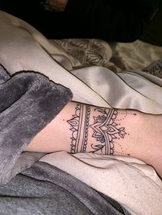 a woman's arm with a tattoo on it and a blanket in the background