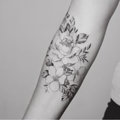 a black and white photo of a woman's arm with flowers tattooed on it