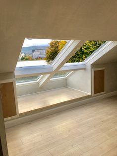 an empty room with skylights and wooden floors in the center, is seen from inside