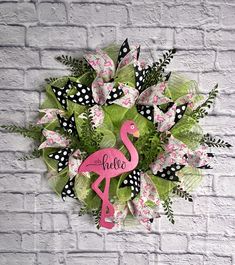 a pink flamingo wreath on a white brick wall with polka dots and green leaves