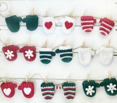 crocheted baby mittens hanging on clothes pins with hearts and clovers attached to them