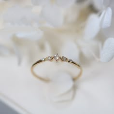 a close up of a wedding ring on a table with white flowers in the background