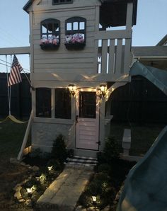 a white house with lights on the front and side windows in the roof, along with steps leading up to an upper level deck