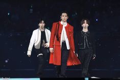 three models walking down the runway in red coats and black pants with white collars