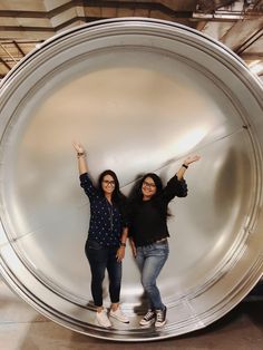 two women standing in front of a large metal object