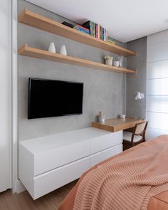 there is a television on the wall in this bedroom with white cabinets and shelving