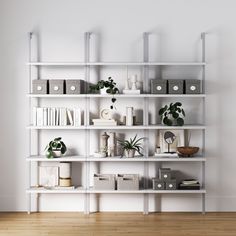 a white book shelf filled with lots of books and plants on top of wooden floors