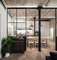 an industrial style kitchen and dining room with glass walls, wood flooring and exposed ceiling