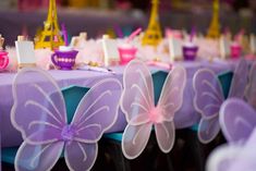 there is a table with purple and pink decorations on it, including butterfly shaped napkins