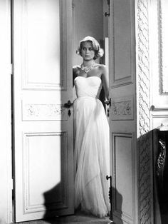 an old photo of a woman in a white dress standing at the entrance to a room