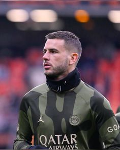 a man in camouflage jacket standing on a soccer field