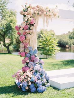 an outdoor wedding ceremony with flowers on the altar and water in the backgroud