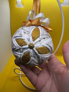 a hand holding a white and gold ornament