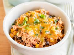 a close up of a bowl of food on a table with a fork and napkin