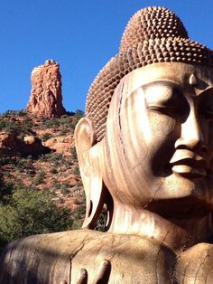 a large buddha statue sitting in front of a mountain