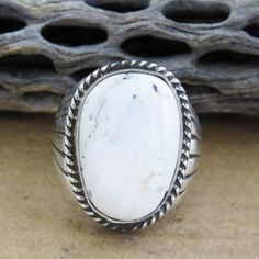 This Native American Navajo White Buffalo Sterling Silver Ring For Men Was Handcrafted With A Uniform, Twisted Rope Design That Surrounds The Stone And Hand-Carved Pin Stripes On The Sterling Silver Shank. This Masculine Ring Was Handmade By One Of Our Favorite, Well-Known Artists, Ray Jack. White Buffalo Turquoise Is A Beautiful White Stone With Black Matrix. White Buffalo Turquoise Was Founded In 1993 In The Only Mine In The World, Which Is Located Near Tonopah, Nevada On The Shoshone Indian R Southwestern White Oval Jewelry, Southwestern Style White Oval Jewelry, Southwestern Style Oval White Jewelry, Southwestern Style White Round Rings, Southwestern Style Oval White Rings, Tonopah Nevada, Silver Ring For Men, Navajo White, White Buffalo Turquoise