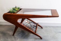 a wooden table with a magazine rack and planter on top