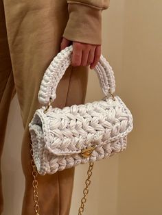 a person holding a white purse with gold chains