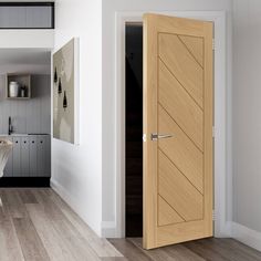 an open door leading to a kitchen and dining room with white walls, wood floors and hardwood flooring