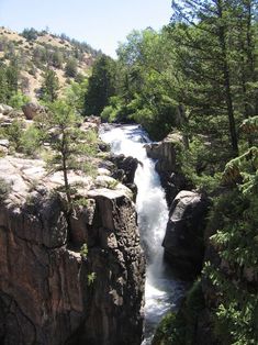 a river running between two large rocks in the middle of a forest with trees on both sides