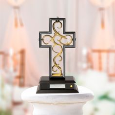 a metal cross sitting on top of a white pedestal