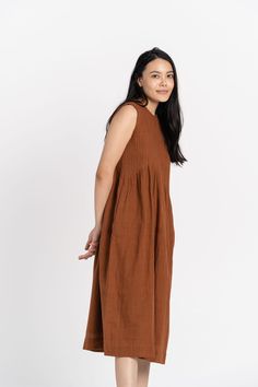 Turtle-neck long brown dress constructed from handwoven organic cotton fabric made by the weavers of Kutch. It has pleat details at the front and back, roomy hidden pockets, and a button closure with a slit at the back. It is ideally worn as a dress for social/outdoor gatherings, casual meets, or for getaways. 100% handwoven cotton. Made in India. "Every style has a different size. Please check the size chart before ordering." Soft Meet Mr. Iqbal, the maker of this dress. Long Brown Dress, Organic Cotton Dress, Sleeveless Long Dress, Pleated Midi Dress, Organic Cotton Fabric, Plus Size Womens Clothing, Brown Dress, Midi Dress Sleeveless, Linen Dress