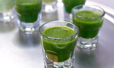 two glasses filled with green liquid on top of a table