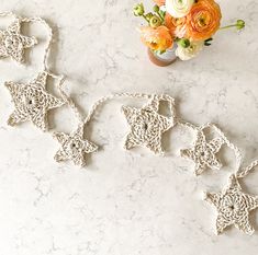 two crocheted stars on a marble surface next to a vase with flowers in it