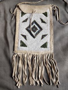 an embroidered bag with fringes and beads on the front, sitting on a gray surface