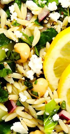 a salad with lemons, spinach and feta cheese is shown in close up