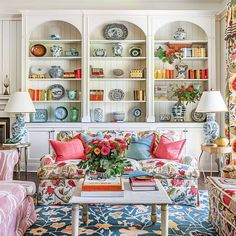 a living room filled with lots of furniture and colorful pillows on top of it's couches