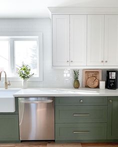 a kitchen with green cabinets and white counter tops, an open dishwasher in the middle