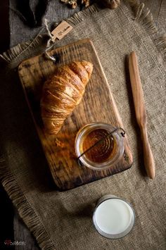 a wooden cutting board topped with a croissant