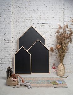 a white brick wall with two black houses on it and some plants in the corner