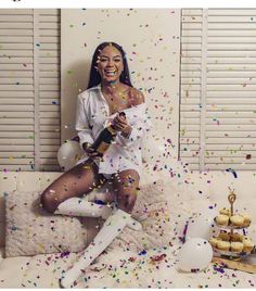 a woman sitting on top of a bed with confetti all over her face