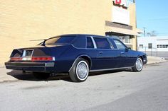 a blue station wagon parked in front of a building