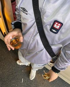 a man holding a glass in his hand and wearing a jacket with patches on it