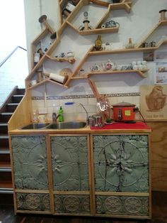 a kitchen area with stairs and shelves on the wall