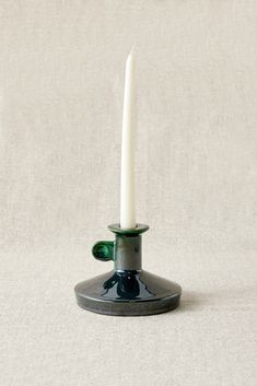 a white candle is sitting on top of a black stand