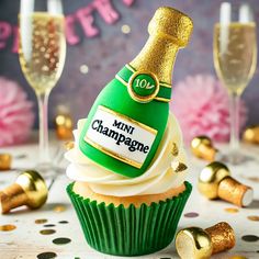 a cupcake with a bottle of champagne on top and some gold confetti