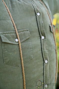 a close up of a person's green shirt with rope on the chest and buttons