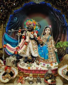 an idol is displayed in front of a backdrop with flowers and other decorations on it