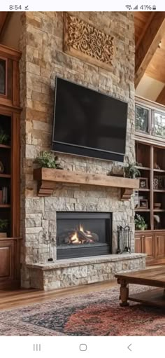 a living room with a large stone fireplace and tv mounted on the wall above it