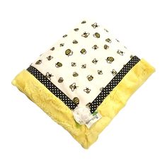 a yellow blanket with black and white bees on it, sitting in front of a white background